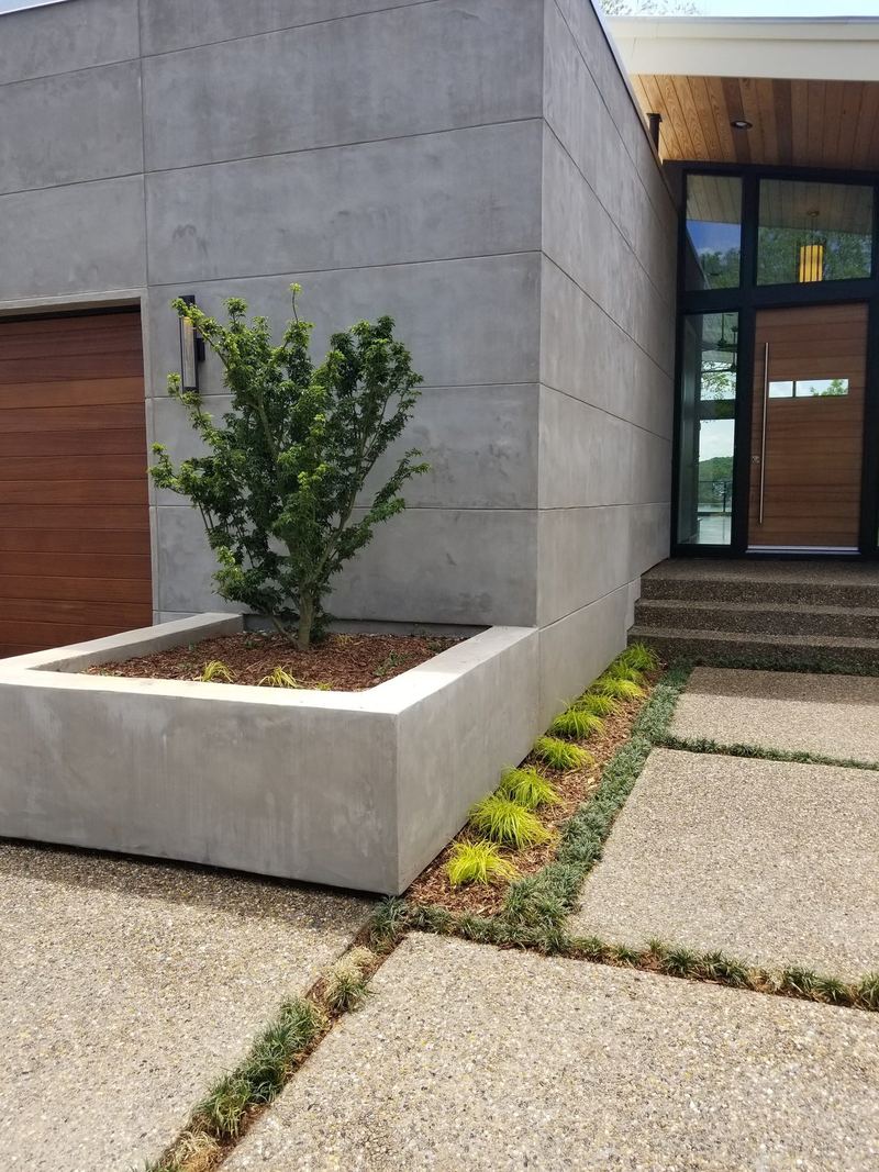 Smooth poured concrete planter walls beside an exposed-aggregate walkway at a modern home